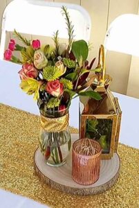 PETITE FLOWER ARRANGEMENT WITH GOLD LANTERN AND CANDLE HOLDER ON WOOD ROUND